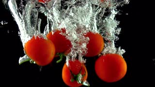 慢动作拍摄许多红色的成熟的西红柿落在水下
